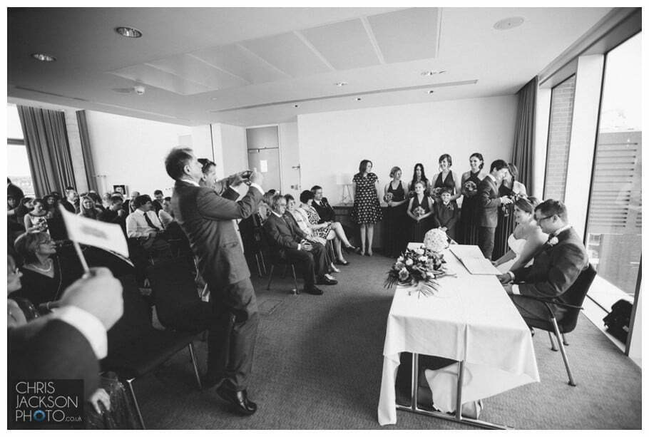 Doubletree by Hilton Wedding Photographer Leeds City Centre Wedding by Chris & Hazel Wedding photography - Tina & Sam 062 guests photographing bride and groom signing register, guests with camera at wedding, guests taking photographs at wedding,