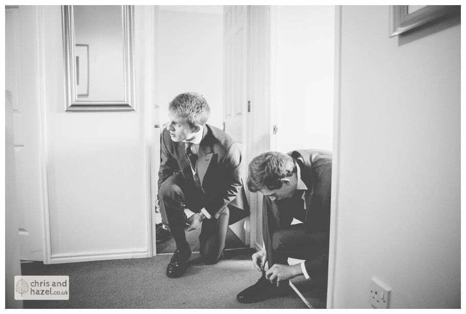 groom tying shoes with usher getting ready preparations york city centre documentary wedding photography ben frankie wedding photographer york wedding photography wedding winter chris and hazel wedding photography york