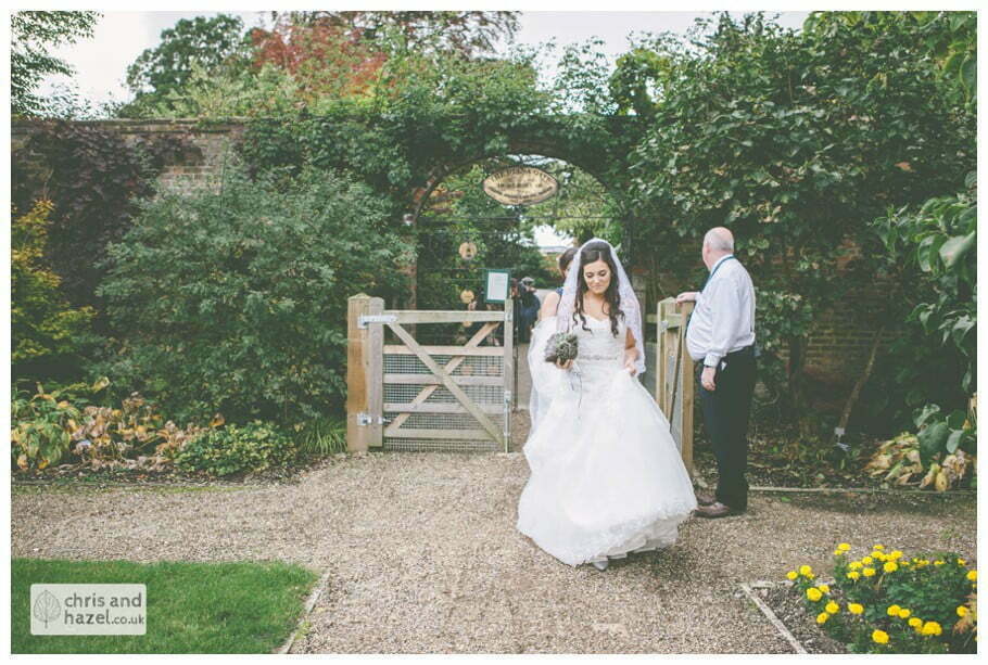 bride walking through gardens to wedding ceremony in greenhouse conservatory documentary Hull Wedding Photographer Bishop Burton College Wedding Photography Hull by Chris and Hazel Wedding Photography Ross laurelin Matulis