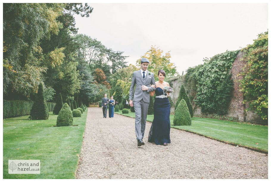 bridesmaid walking with groomsmen down aisle wedding ceremony in greenhouse conservatory documentary Hull Wedding Photographer Bishop Burton College Wedding Photography Hull by Chris and Hazel Wedding Photography Ross laurelin Matulis