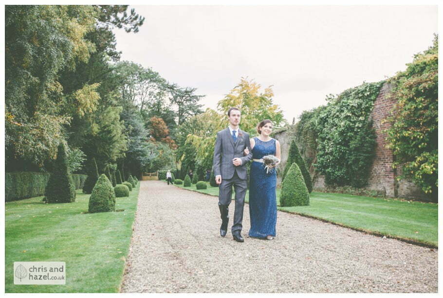 bridesmaid walking with groomsmen down aisle wedding ceremony in greenhouse conservatory documentary Hull Wedding Photographer Bishop Burton College Wedding Photography Hull by Chris and Hazel Wedding Photography Ross laurelin Matulis