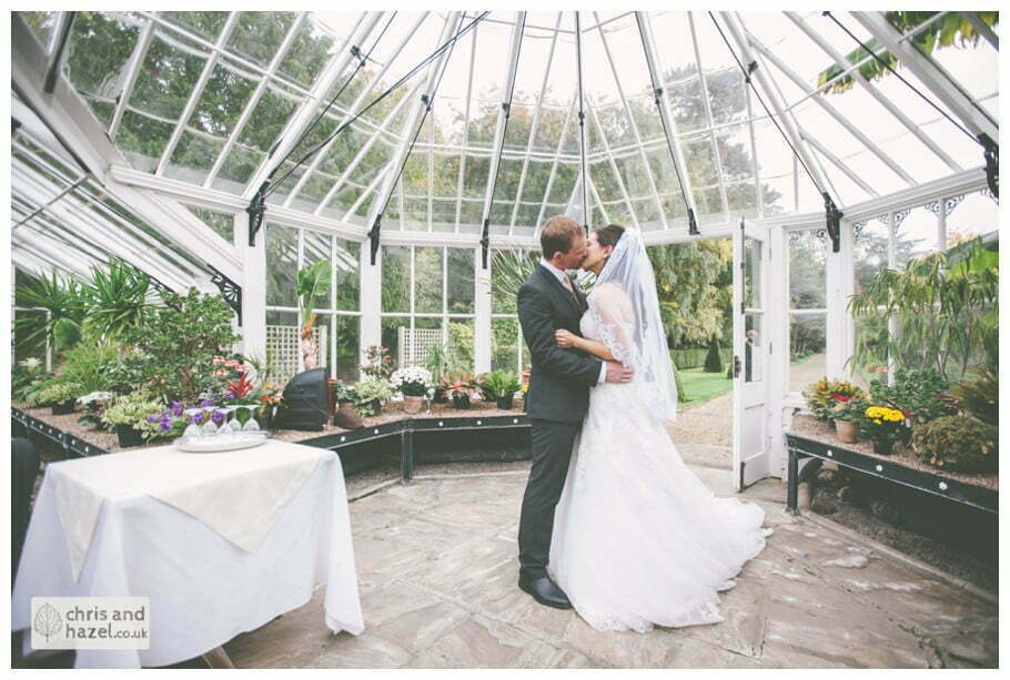 bride and groom first kiss wedding ceremony in greenhouse conservatory documentary Hull Wedding Photographer Bishop Burton College Wedding Photography Hull by Chris and Hazel Wedding Photography Ross laurelin Matulis
