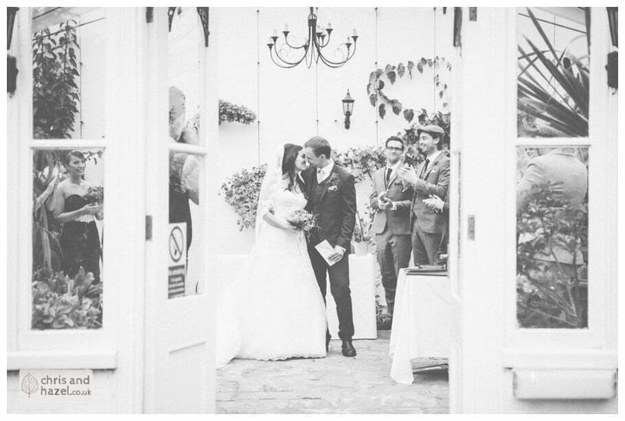 bride and groom first kiss wedding ceremony in greenhouse conservatory documentary Hull Wedding Photographer Bishop Burton College Wedding Photography Hull by Chris and Hazel Wedding Photography Ross laurelin Matulis
