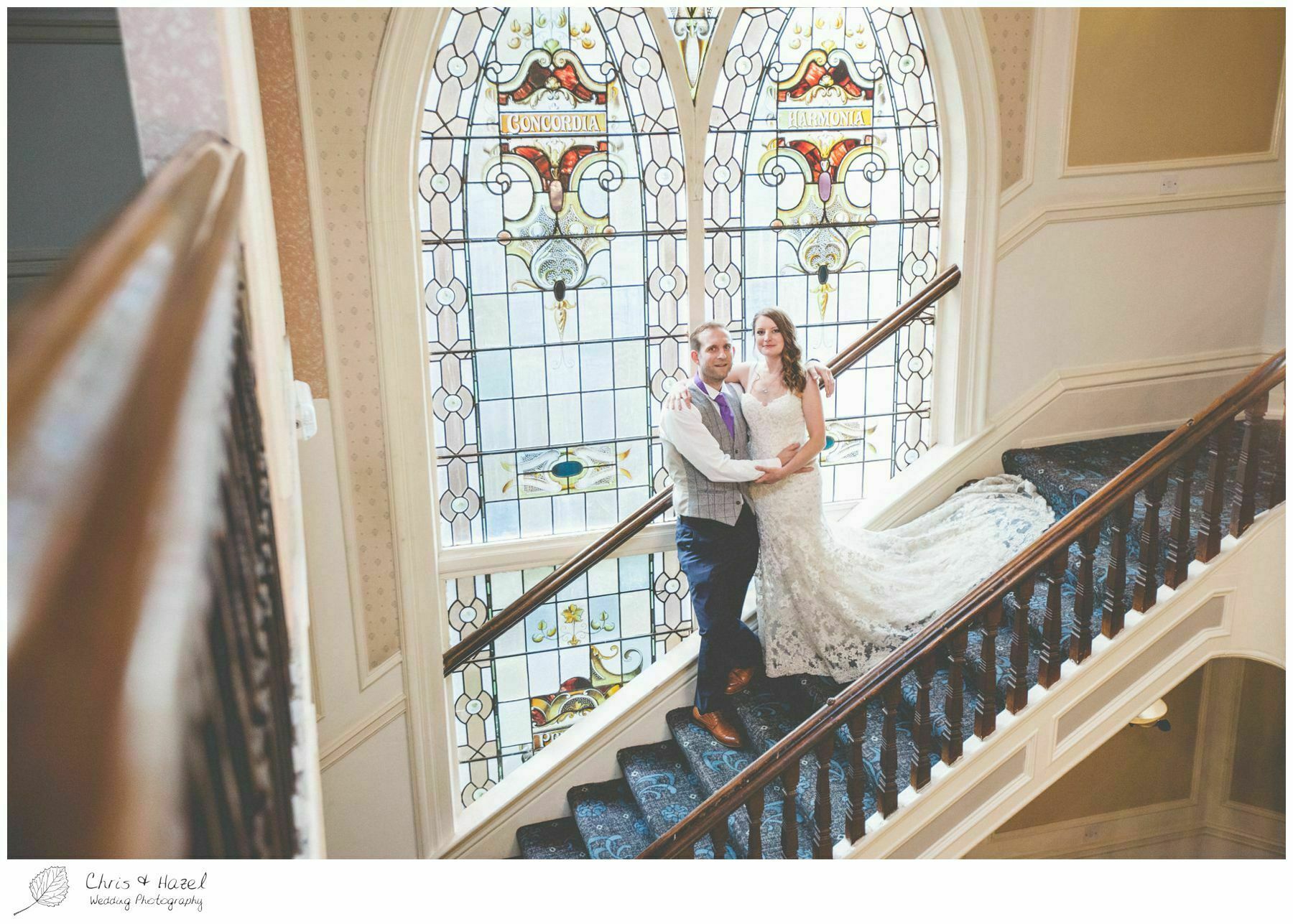 bride and groom on staircase, wooden staircase, old fashioned staircase, stain glass window, documentary wedding photography, the cairn hotel, the cairn hotel wedding photographer, wedding photography harrogate, wedding photography yorkshire, chris and hazel wedding photography, scott Dixon, caroline ellis, caroline Dixon
