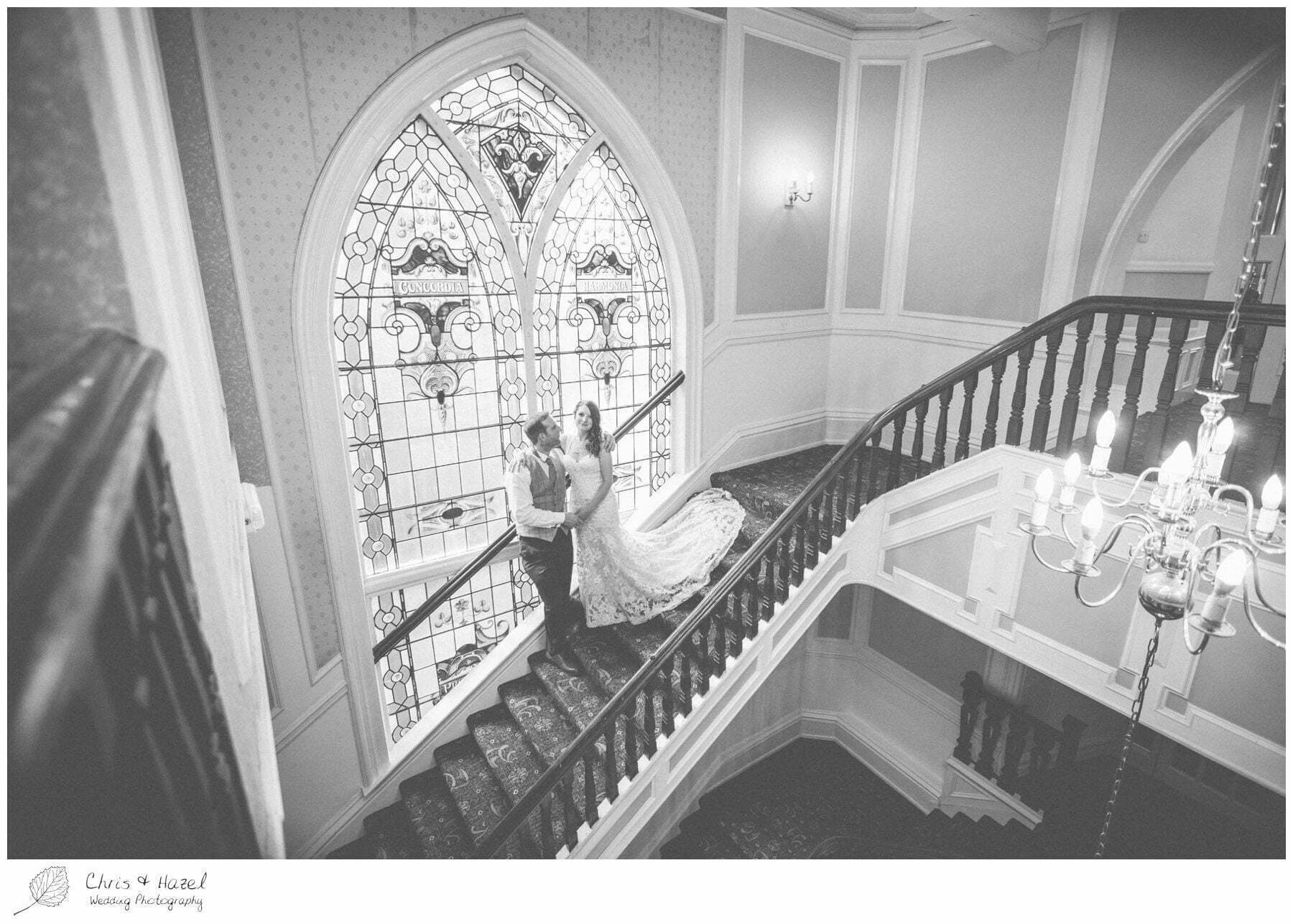 bride and groom on staircase, wooden staircase, old fashioned staircase, stain glass window, documentary wedding photography, the cairn hotel, the cairn hotel wedding photographer, wedding photography harrogate, wedding photography yorkshire, chris and hazel wedding photography, scott Dixon, caroline ellis, caroline Dixon